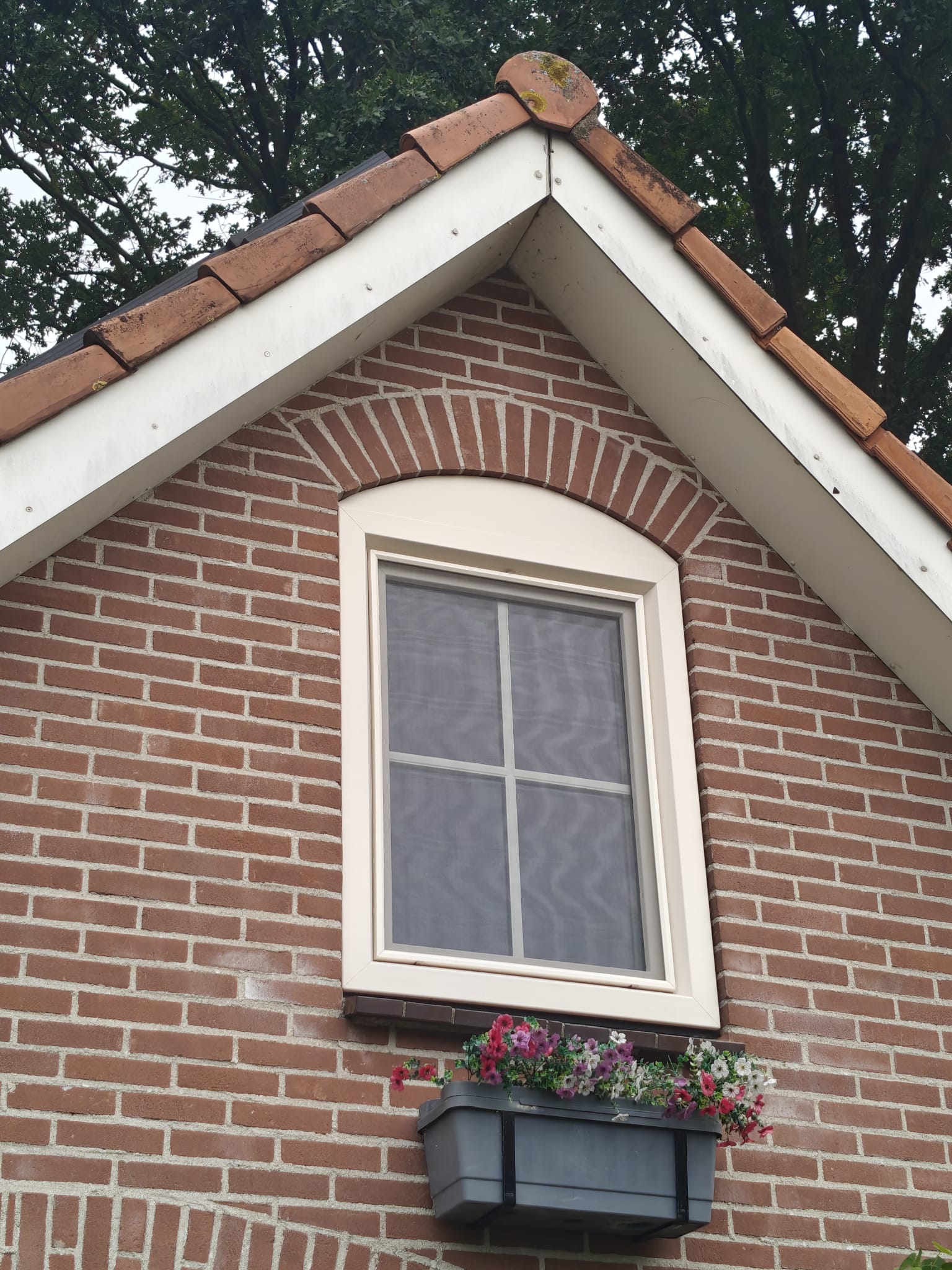 Crème kunststof draaikiepraam met roedes in de kopgevel van BSO By Bentley's in Neede